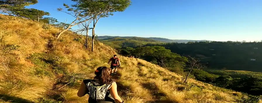 Trilheiras de mochila na trilha dourada da encosta, com o vale verde abaixo